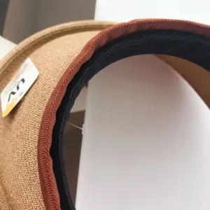 Detalle en primer plano del sombrero de paja con borde marrón y banda interior negra.