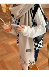 Detailed shot of beige knit tassel scarf worn in lifestyle scene, cozy winter fashion accessory.