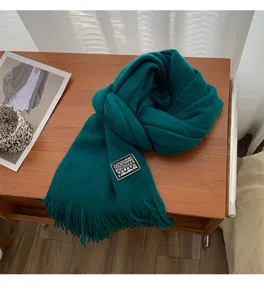 Detailed shot of a dark green knitted winter scarf featuring soft texture and stylish fringe ends.