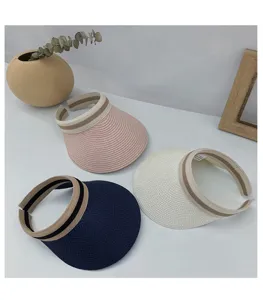 Detailed view of summer straw sun visors with striped bands in pink, navy, and beige.