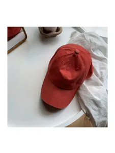 Detailed closeup view of a vintage washed red cotton baseball cap on a clean white table.