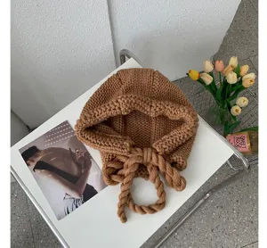 Cozy knitted braided tie beanie hat, winter warm ear-flap cap, elegant casual women streetwear.