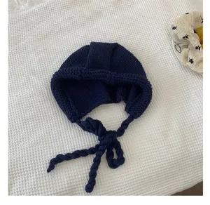 Chic dark blue knitted earflap hat with braided ties, warm and stylish winter accessory.