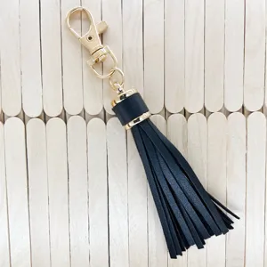 Black PU leather tassel keychain detail, gold lobster clasp accessory for bags and keys.
