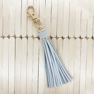 Grey leather tassel keychain with gold lobster clasp, chic bag charm and stylish accessory.