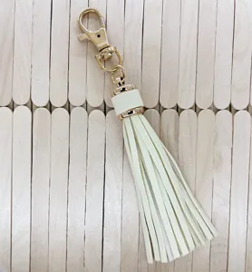 Cream faux leather tassel keychain with gold hardware, perfect bag charm and DIY accessory.