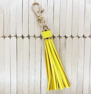 Yellow leather tassel keychain with gold metal hardware, ideal for DIY bag charms and accessories.