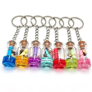 Close-up of colorful mini glass wish bottle keychains featuring tiny shells, sand, and scrolls inside.