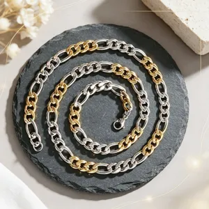 Vue détaillée d'un collier chaîne Figaro bicolore or et argent sur ardoise noire