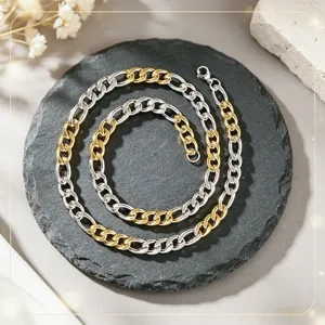 Vue détaillée d'un collier chaîne bicolore argent et or en acier inoxydable sur pierre noire.