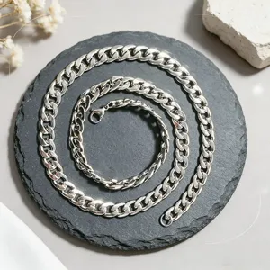 Gros plan d'un collier à maillons cubains en acier inoxydable sur une base en pierre.