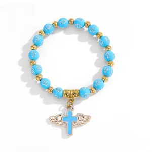 Vista detallada de una pulsera de cuentas azul claro con colgante de cruz alada