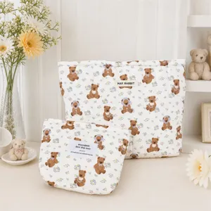 Gros plan de deux trousses de toilette matelassées blanches avec ours et fleurs