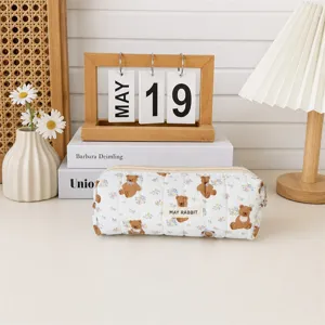Gros plan d'une trousse à maquillage matelassée à motif ours dans un décor de bureau