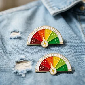 Detailed macro shot of My Social Battery enamel pins pinned onto a blue denim jacket