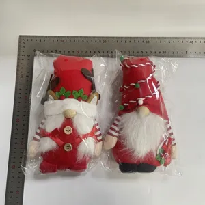 Dos festivos gnomos navideños rojos en su empaque medidos con una regla metálica profesional