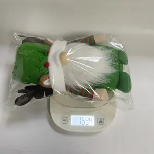 Báscula digital que muestra el peso de un gnomo de Navidad verde empaquetado