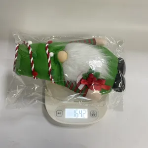 Medición del peso de un gnomo de Navidad de peluche verde marcando 164,2 g en báscula