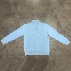 Vista dettagliata di una felpa jacquard azzurra da uomo con collo alto e toppa sul gomito marrone.