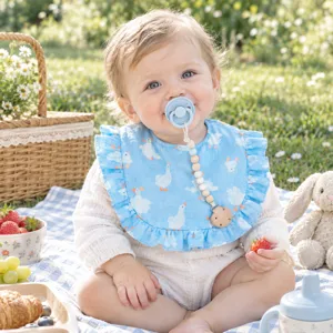 Un simpatico bambino indossa un bavaglino in mussola blu con volant a un picnic
