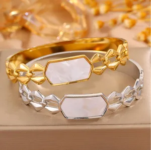 Detailed view of geometric stainless steel bangles featuring white mother of pearl inlay