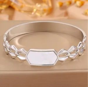 Macro view of silver stainless steel bangle with geometric links and white shell inlay