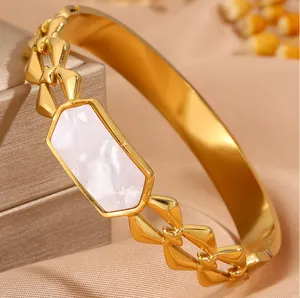 Detail shot of a gold-toned stainless steel bracelet with a hexagonal white shell inlay