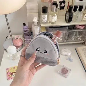 Detail of cute onigiri-style corduroy coin purse with crying face embroidery.