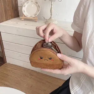Detailed view of a cute brown cartoon face corduroy coin purse being used to store metal keys