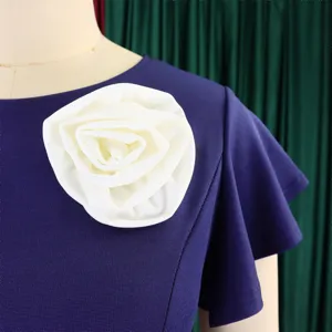 Close-up detail of white rose flower embellishment on a purple ruffle sleeve dress.