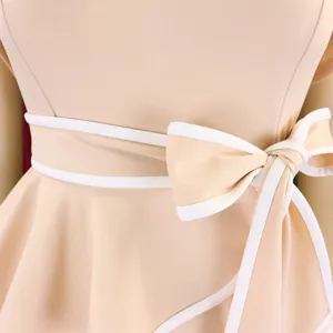 Close-up of elegant bow tie detail on an apricot midi dress with refined white piping