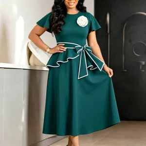 Detail of elegant dark green midi dress with white ruffled bow and flower brooch.