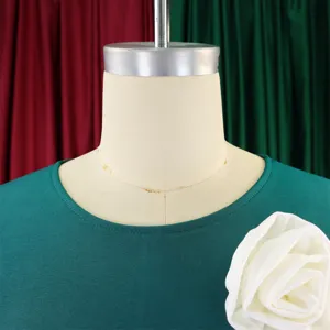Close-up detail of a dark green dress neckline with a large white fabric flower.