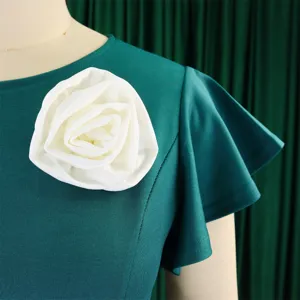 Close-up of white fabric flower decoration and ruffle sleeve on dark green dress