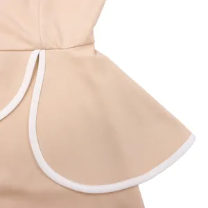 Close-up showing the elegant ruffle peplum design with white piping on a beige dress