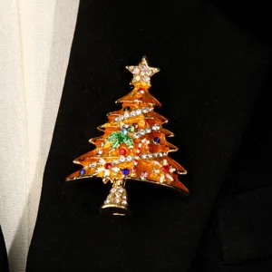 Detaillierte Makroansicht einer goldenen Weihnachtsbaum-Brosche mit bunten Kristallakzenten.