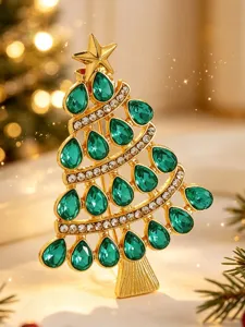 Makro-Detailansicht einer goldenen Weihnachtsbaumbrosche mit smaragdgrünen Edelsteinen.