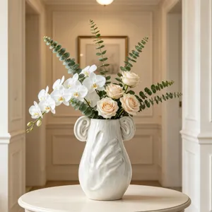 Un elegante vaso in ceramica bianca con rilievo a mano e bellissimi fiori artificiali