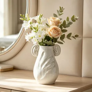 Dettaglio ravvicinato di un vaso in ceramica bianca con motivo a mano e rose su mobile