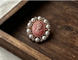 Gros plan d'une broche camée Victoria vintage avec relief rose, perles et strass.