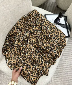 Dettaglio di un elegante foulard di seta quadrato con stampa leopardata su una sedia bianca.