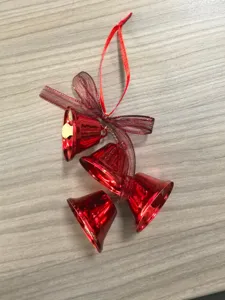Detailed view of red metallic Christmas bell ornaments with ribbon bow on wooden surface.