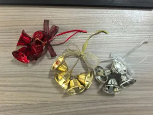 Close-up of three metallic Christmas bell ornaments in red, gold, and silver on wood background
