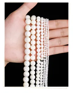 Detailed view of white mother-of-pearl shell round beads in various sizes for DIY jewelry