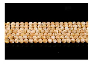 Macro view of polished natural trochus shell round beads showing unique pearlescent swirl patterns