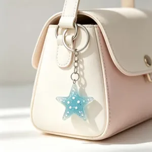 Glittering blue starfish keychain bag charm detail, sparkling resin pendant for women.