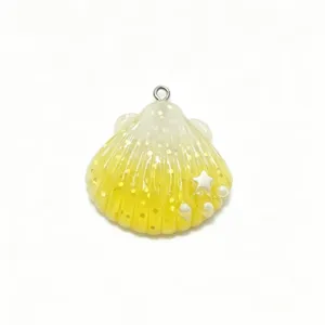 Detailed close-up of a yellow gradient resin shell charm with glitter, tiny star, and pearls.