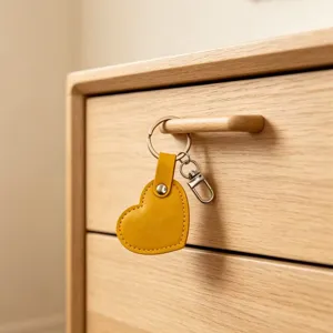 Yellow heart leather keychain hanging on wooden drawer, stylish bag charm DIY pendant.