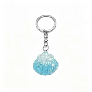 Close-up detail of a cute blue glitter seashell keychain with a durable silver metal ring.