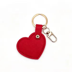 Red heart-shaped leather keychain detail showing exquisite stitching and golden ring hardware.